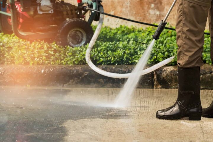Worker cleaning driveway with gasoline high pressure washer ,professional cleaning services.High pressure deep cleaning.